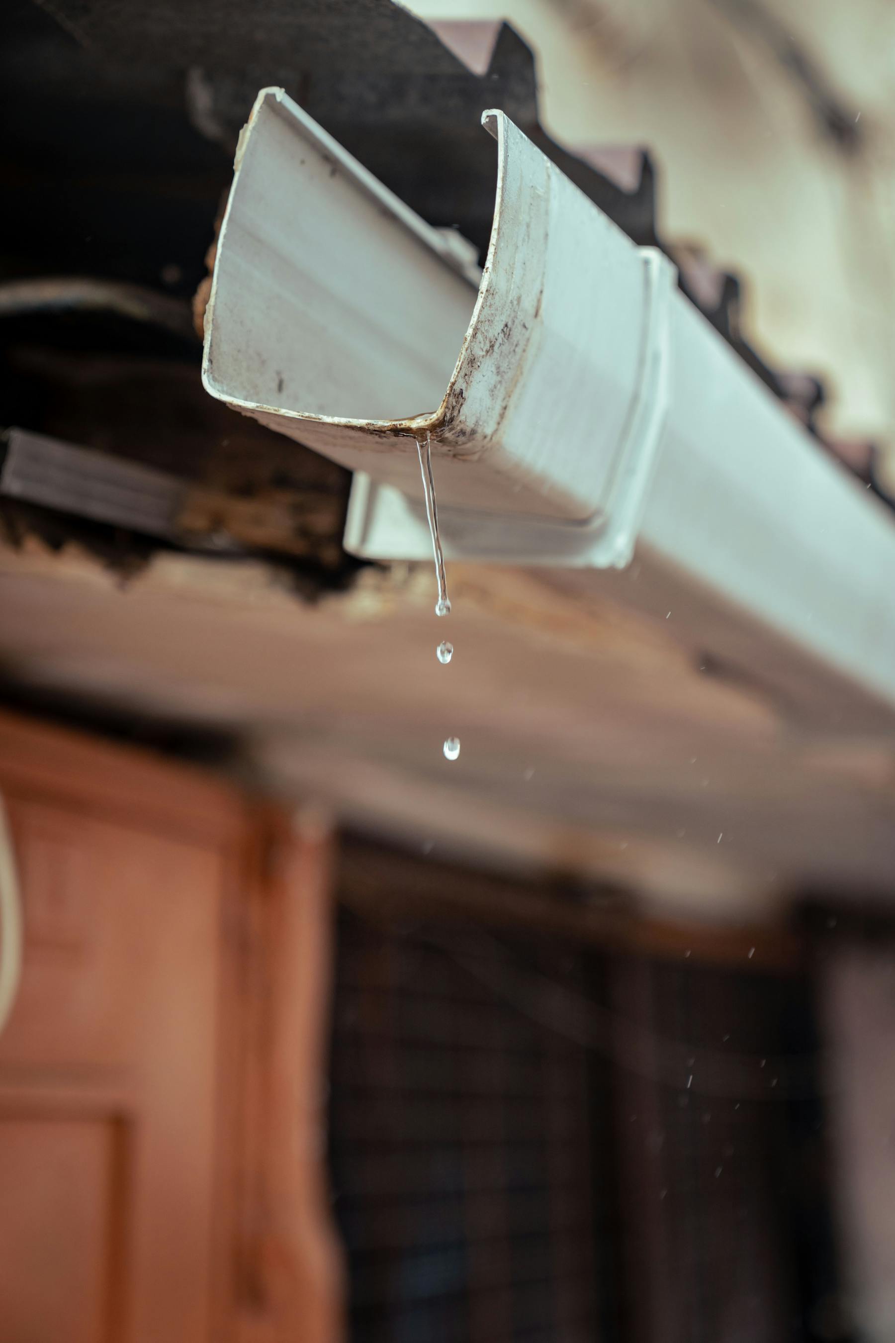 Close-up of a damaged roof section with cracked flashing and missing shingles, before repair