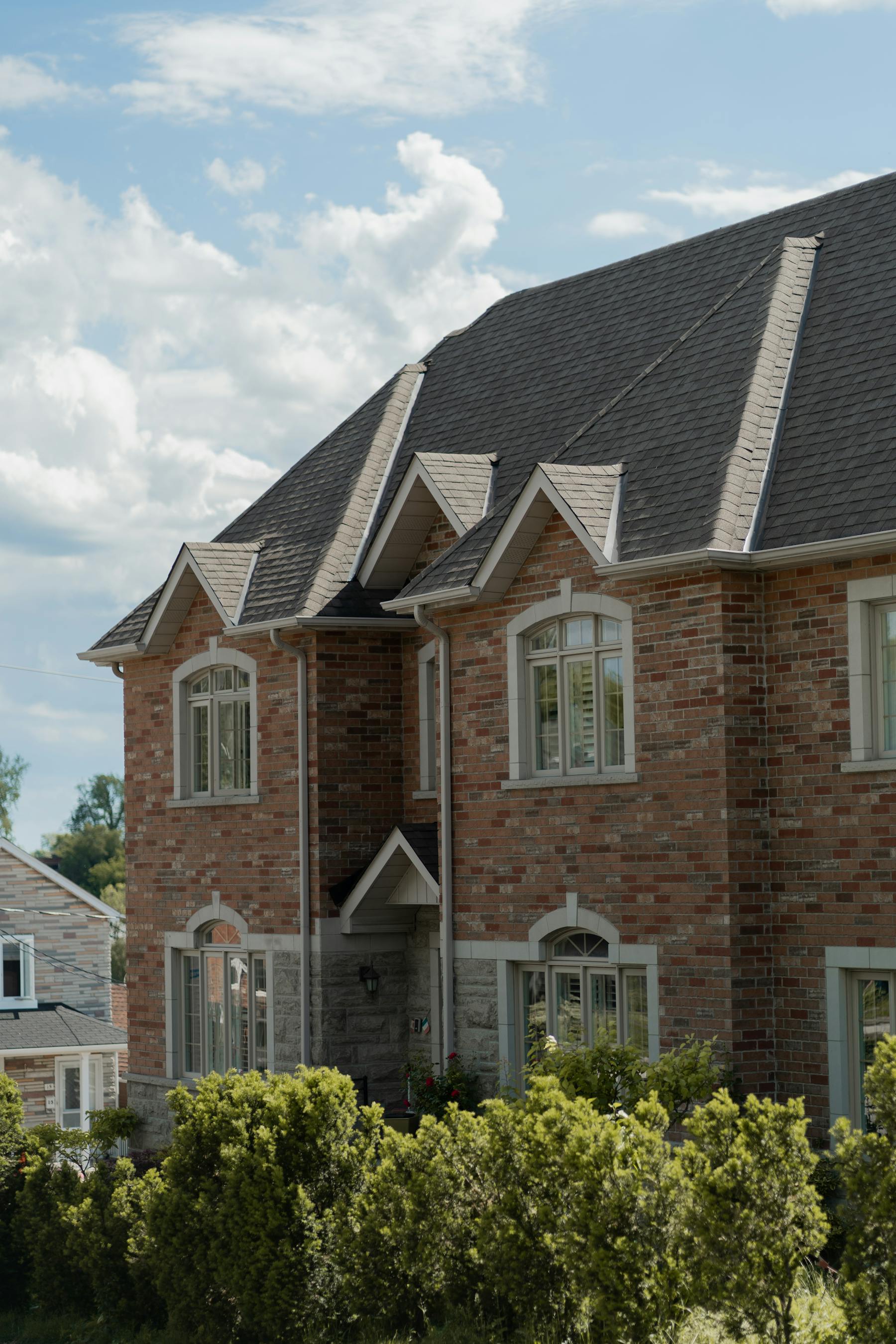 Classic red brick Toronto two storey home with a steep new dark roof