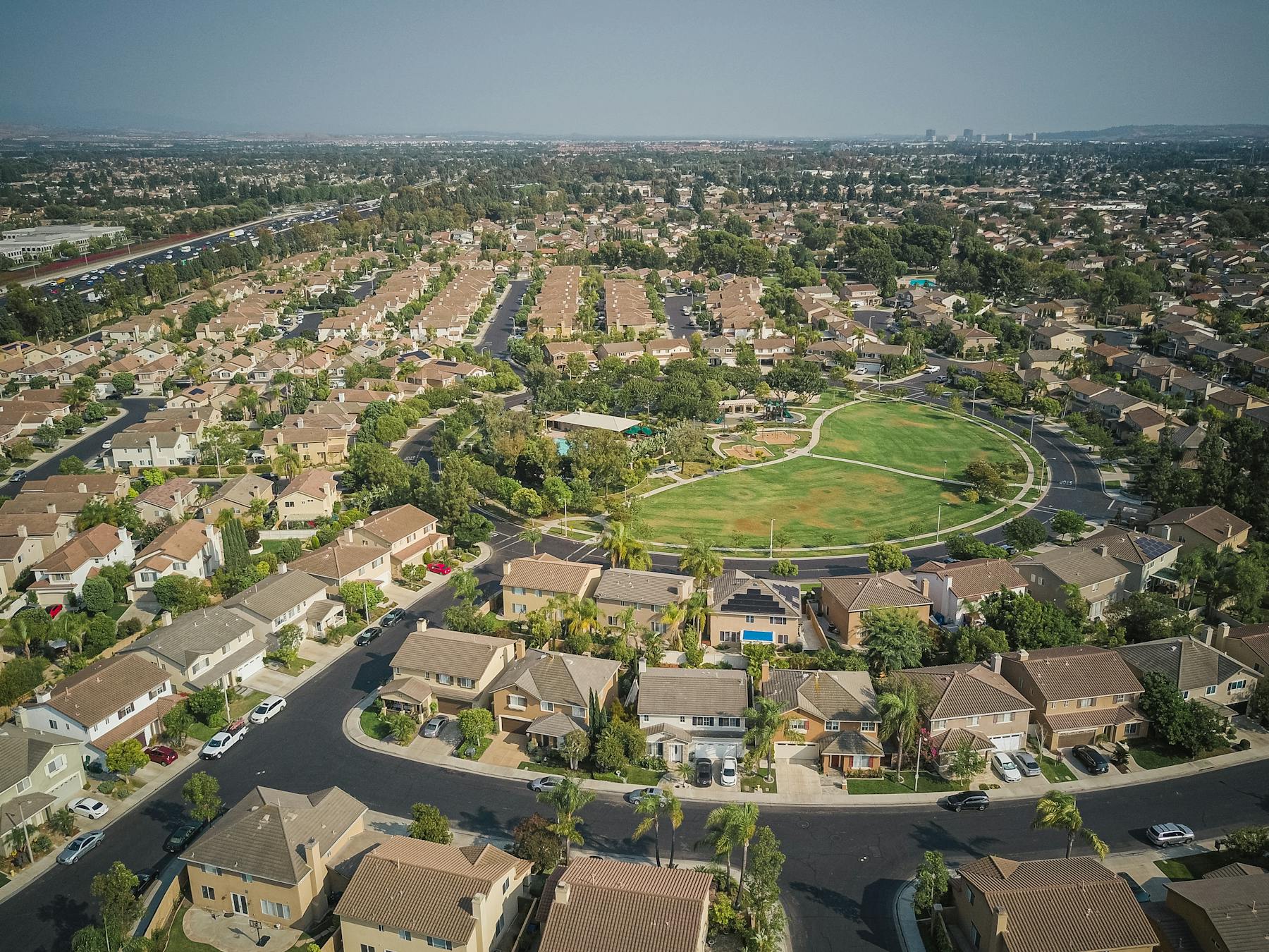 Drone view of a GTA subdivision with orderly rooflines around a green park