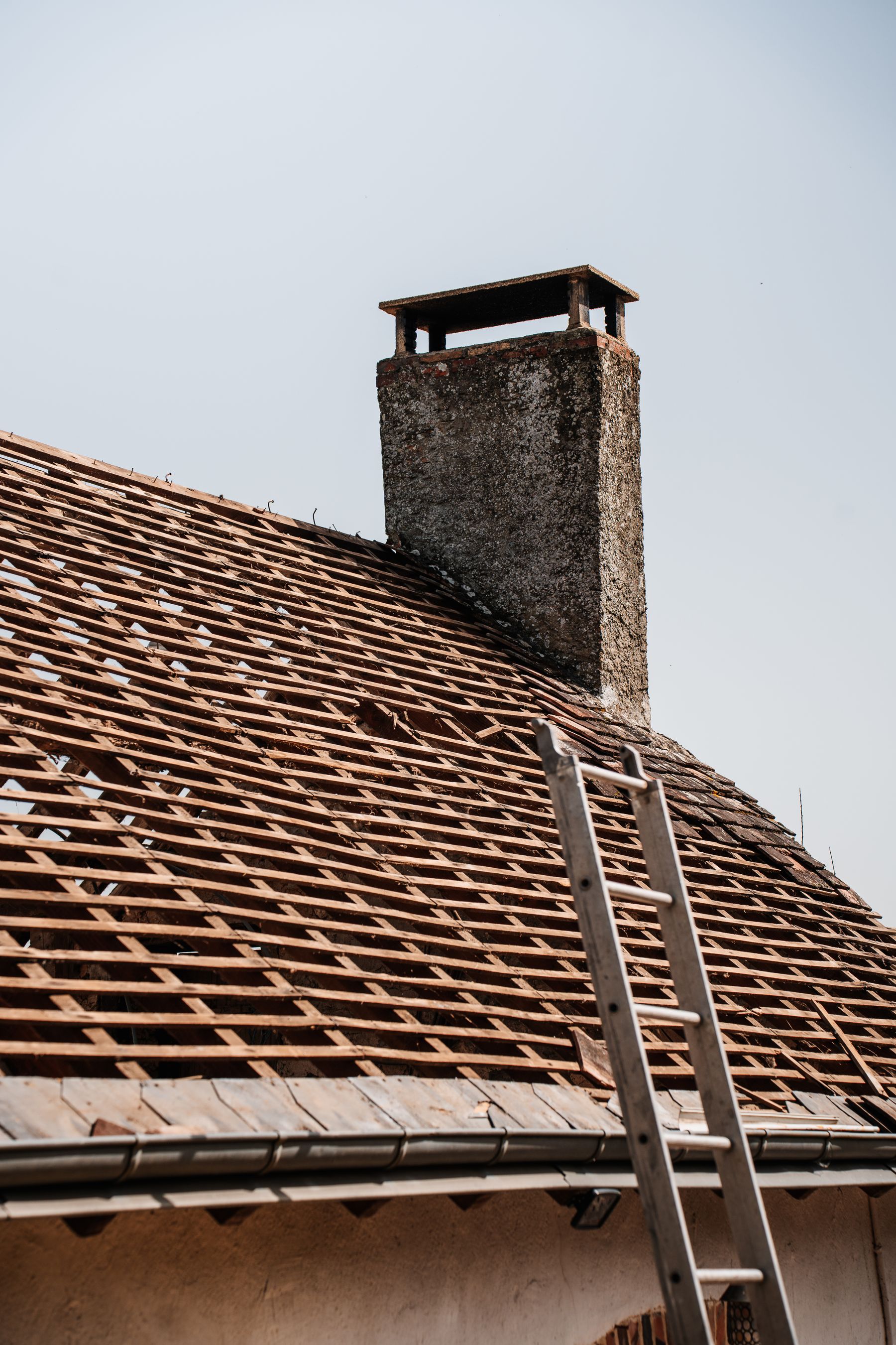 Weathered, moss-flecked asphalt shingle roof partway through renovation