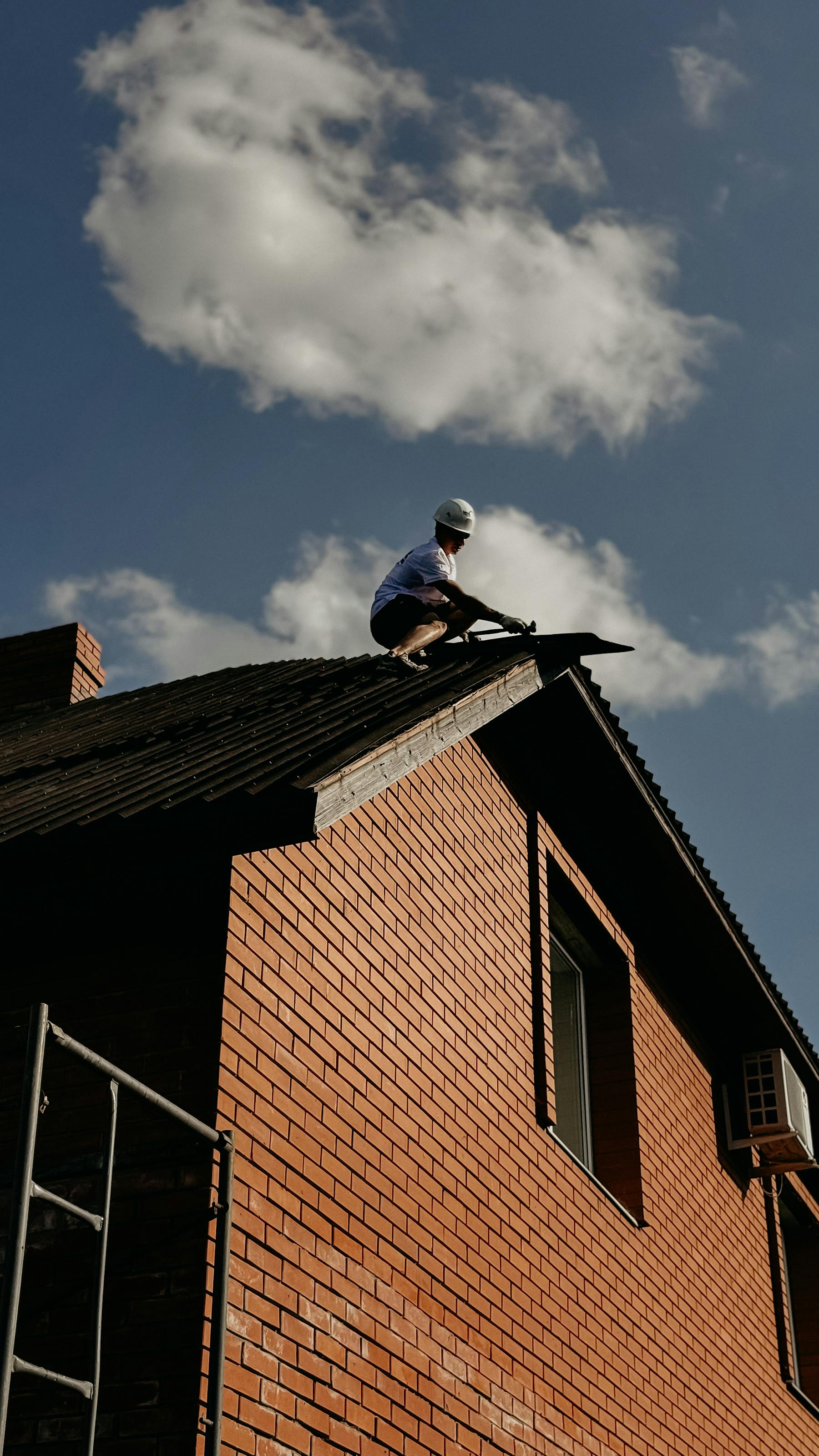Roofer securing an emergency tarp over wind-damaged shingles after a storm